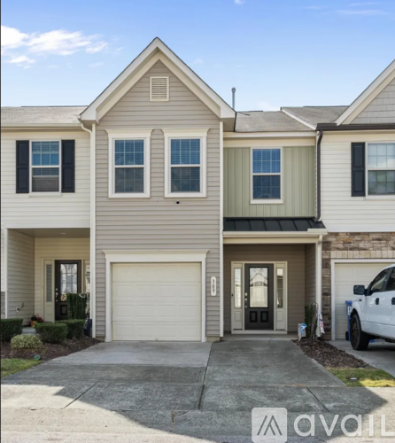 A two-story house with a garage and a car parked in front.