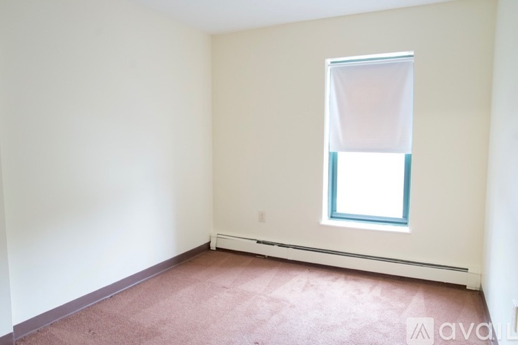 A room with a window and a carpeted floor.