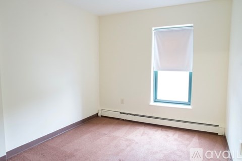 A room with a window and a carpeted floor.