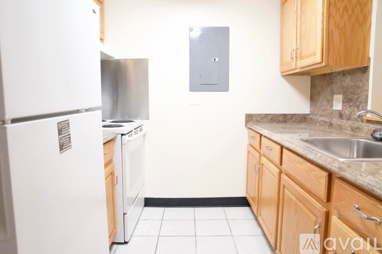 A kitchen with a white fridge, wooden cabinets, and a stainless steel dishwasher.