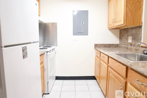 A kitchen with a white fridge, wooden cabinets, and a stainless steel dishwasher.