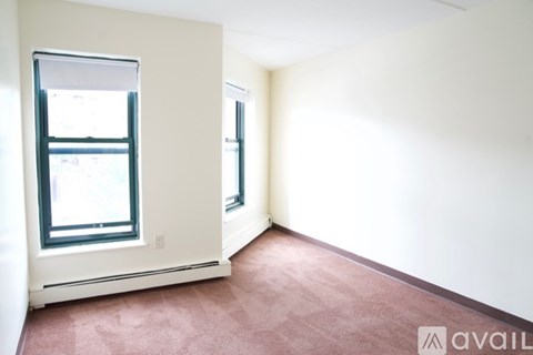 A room with a window and a carpeted floor.