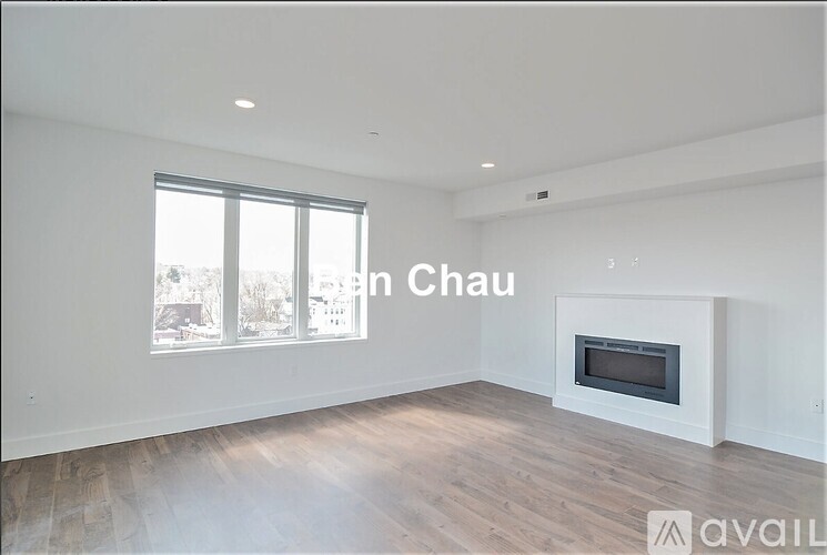 A large, empty room with a fireplace and a window overlooking a snowy landscape.