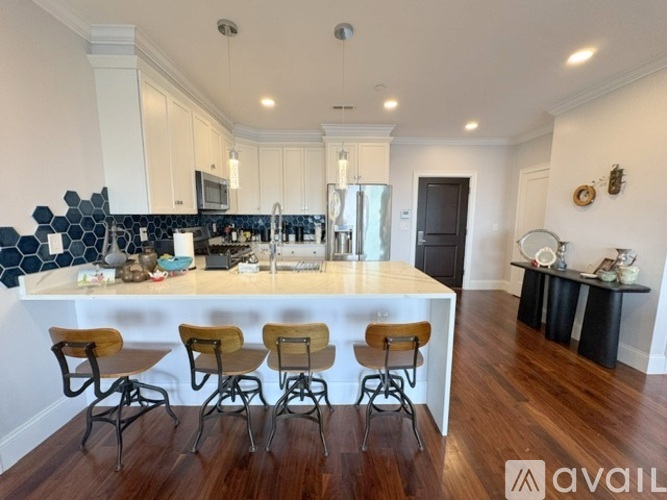 A kitchen with a white countertop and wooden bar stools.