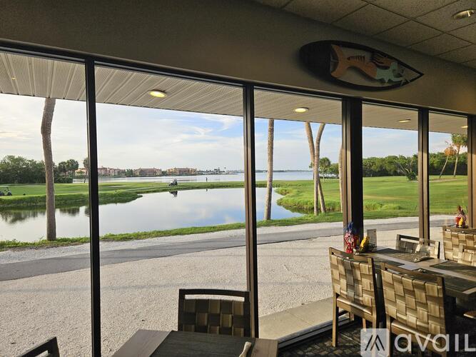 A view of a golf course from a room with a table and chairs.