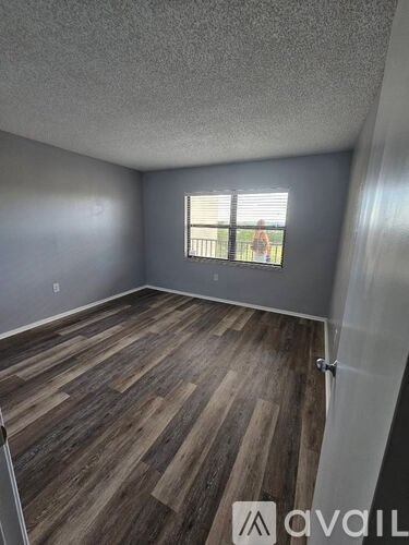 A room with wooden flooring and a window with blinds.
