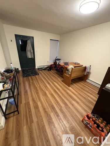 A room with wooden flooring and a bed in the corner.