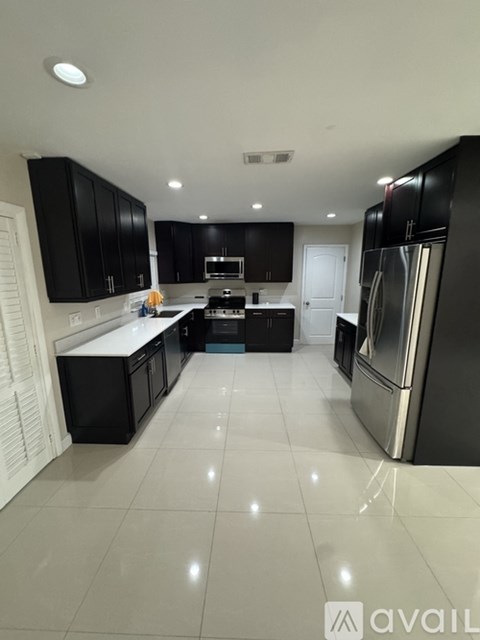 A modern kitchen with black cabinets and stainless steel appliances.