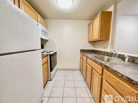 A kitchen with a white refrigerator and wooden cabinets.