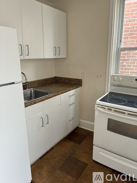A kitchen with white cabinets and a white fridge.