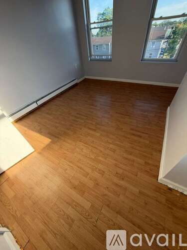 A room with wooden flooring and a window showing a view of buildings outside.