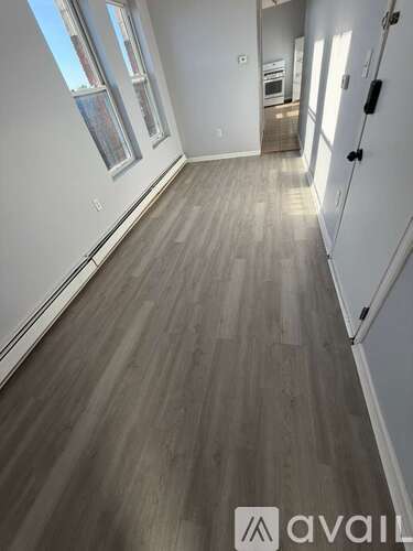 A long hallway with wood flooring and white walls.