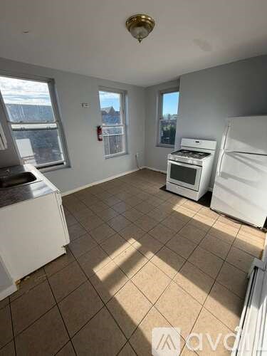 A kitchen with white appliances and tiled flooring.