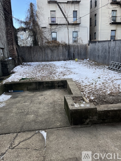 A backyard with a concrete patio and a wooden fence.