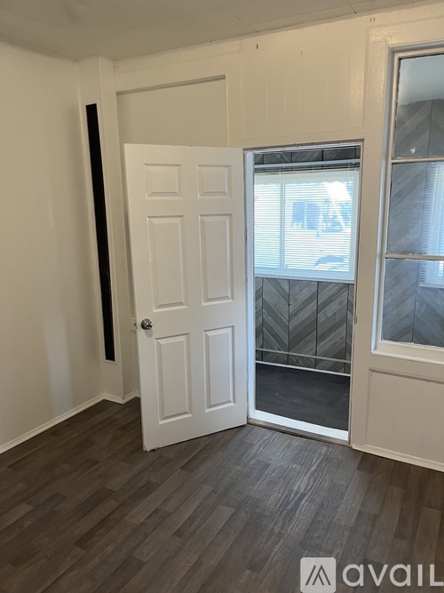 A room with a white door and a window with a view of a building outside.