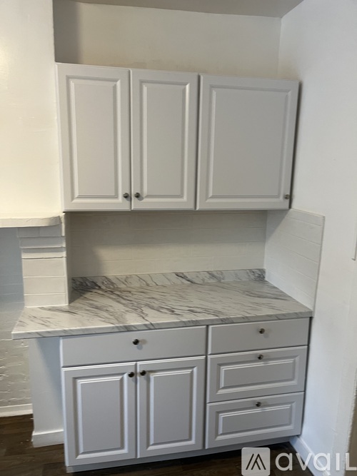A kitchen with white cabinets and a marble countertop.
