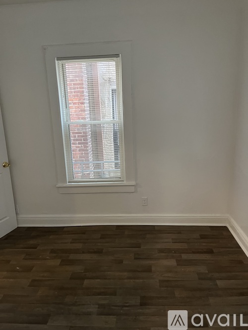 A room with a window and wooden flooring.