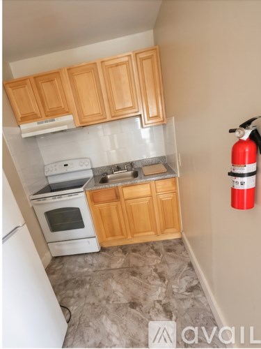 A kitchen with wooden cabinets and a red fire extinguisher on the wall.