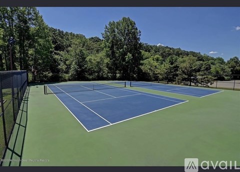 A tennis court surrounded by trees and a fence.