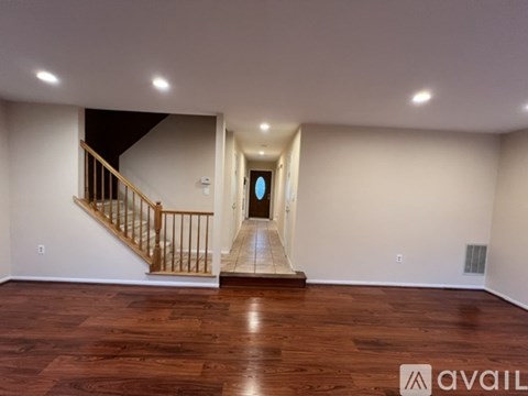 A spacious room with wooden floors and a staircase leading to another level.