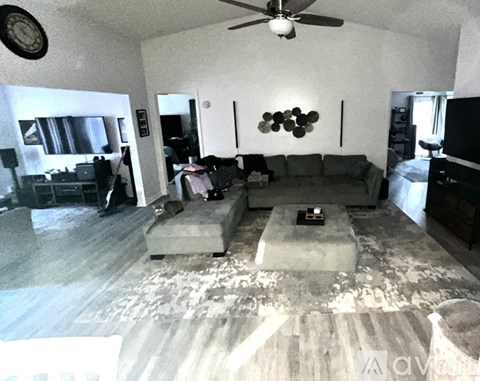 A living room with a grey couch and a fan on the ceiling.