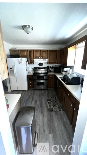 A kitchen with a white fridge and a stainless steel trash can.