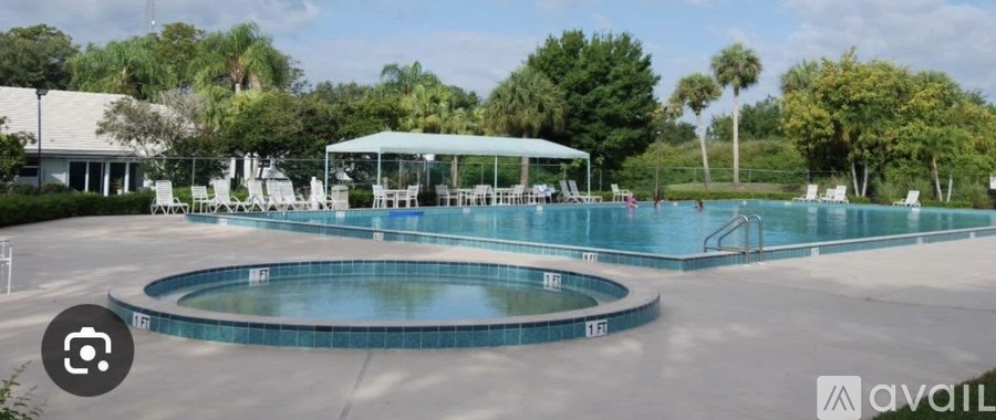 A large outdoor swimming pool with a round hot tub in the middle.