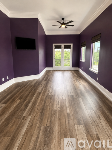 A spacious room with wooden flooring and a ceiling fan.