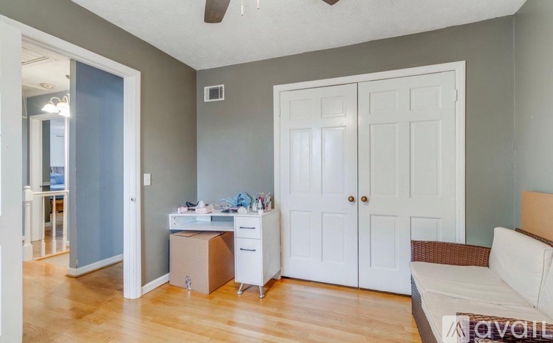 A room with a white couch, a desk with a computer, and a white cabinet.