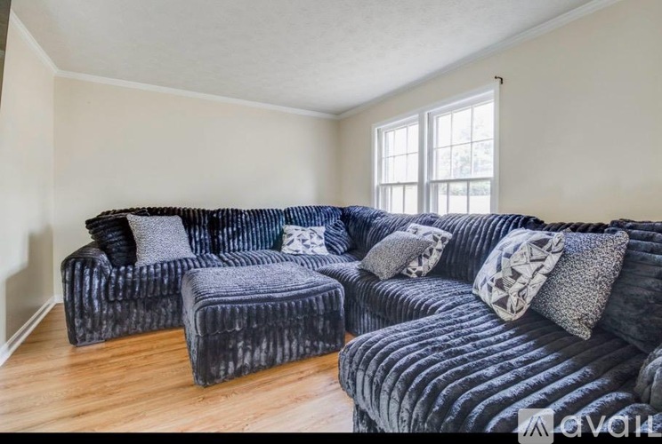 A living room with a large black couch and a small ottoman.