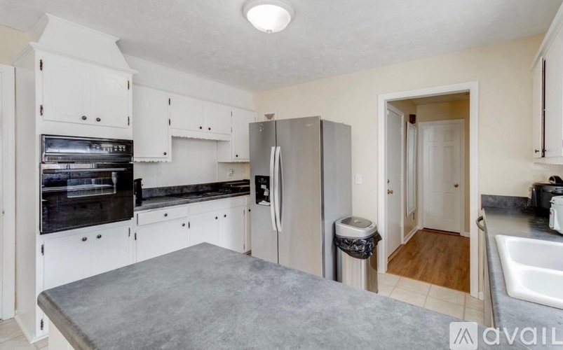 A kitchen with white cabinets and a refrigerator.