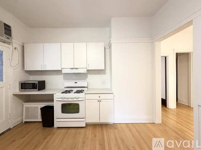 A kitchen with white cabinets and a black trash can.