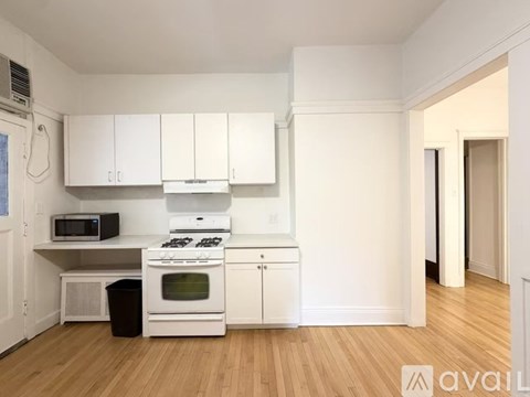 A kitchen with white cabinets and a black trash can.