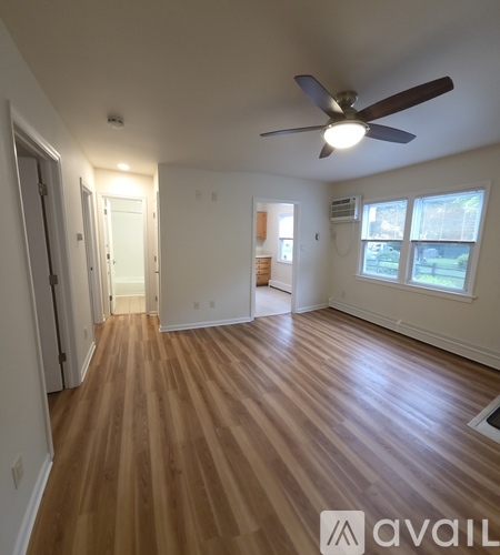 A room with a ceiling fan and wooden flooring.