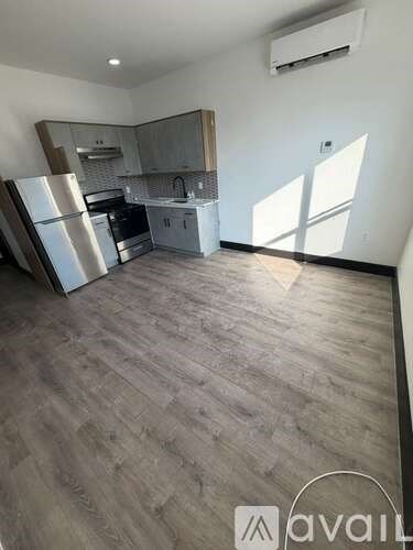 A kitchen with a refrigerator and oven in a room with wooden flooring.