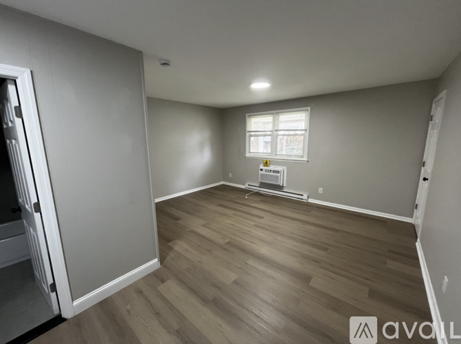 A room with wooden flooring and a window with blinds.