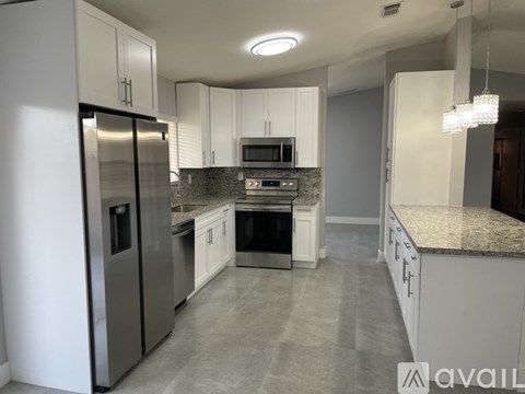 A kitchen with a refrigerator, microwave, oven, and cabinets.