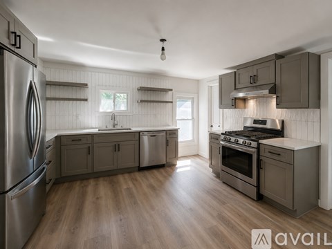 A modern kitchen with wooden floors and stainless steel appliances.