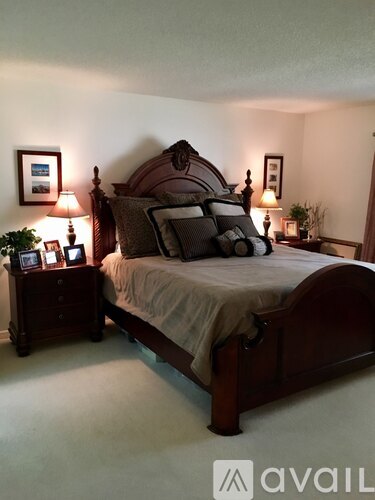 A bedroom with a bed, nightstands, and pictures on the wall.