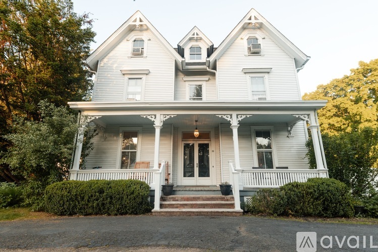 A white two-story house with a porch and a front yard.
