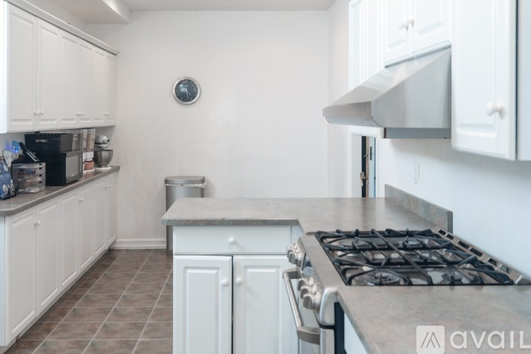 A kitchen with white cabinets and a stove top oven.