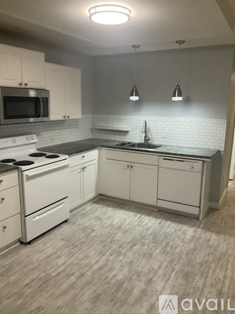 A kitchen with white cabinets and a black countertop.