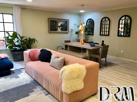 A living room with a pink couch and a painting on the wall.