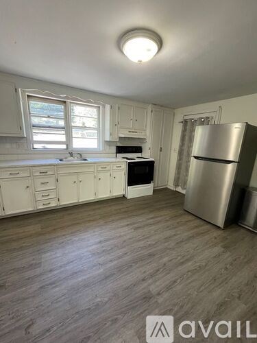 A kitchen with white cabinets and a wooden floor.