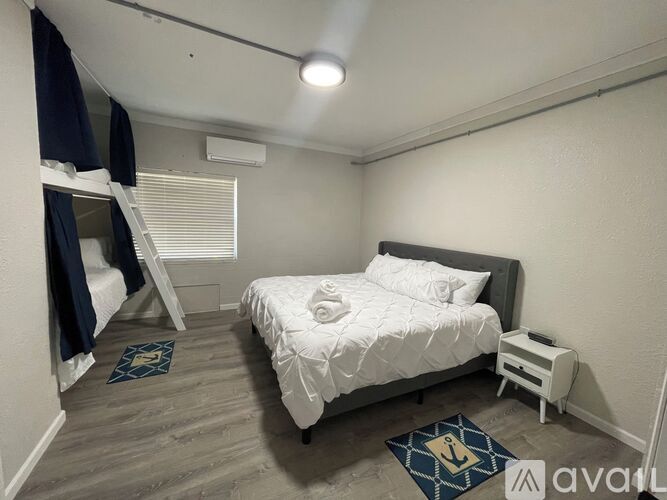 A bedroom with a white bed and a small nightstand.