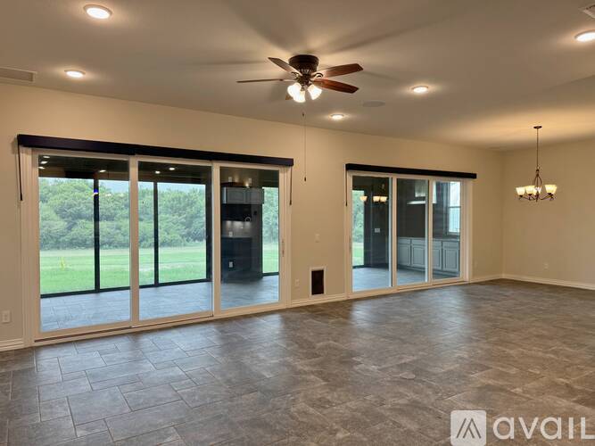 A spacious room with a ceiling fan and sliding glass doors.