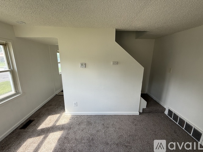 A room with a carpeted floor and a window letting in sunlight.