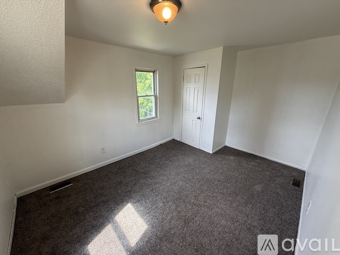 A room with a carpeted floor, a window, and a door.