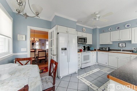 A kitchen with white appliances and a table with chairs.