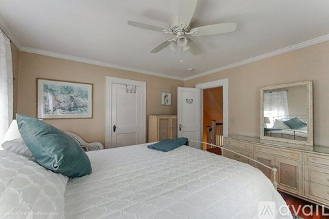 A bedroom with a large bed and a ceiling fan.